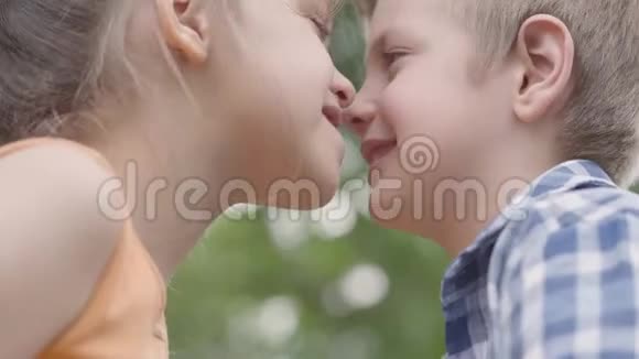 可爱的男孩和女孩坐在公园里试图揉鼻子玩得开心一对快乐视频的预览图