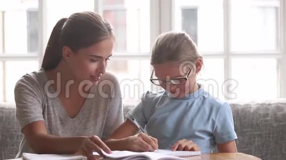 年轻的母亲帮助小女儿完成学业视频的预览图