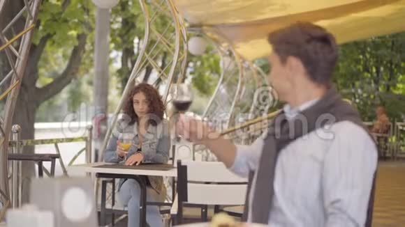 年轻人喝着红酒坐在前台举起酒杯看着坐在前台的漂亮女人视频的预览图