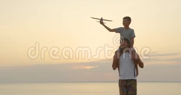 快乐的父子在日落时一起玩飞机玩具幸福的家庭在户外散步视频的预览图