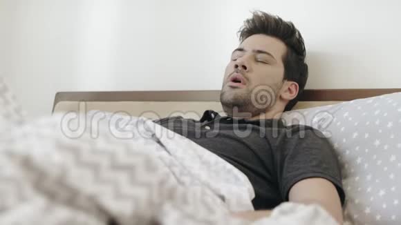 早上睡觉的人在床上打哈欠帅哥在卧室里伸懒腰视频的预览图