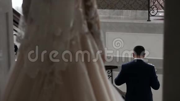 新娘穿着漂亮的婚纱走下台阶走向等待的新郎视频的预览图