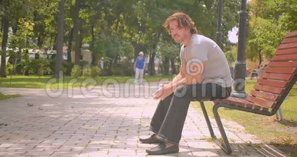 户外公园里坐在长凳上迷人的白种人的特写肖像视频的预览图