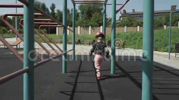一个穿着保护性运动装备的小女孩在城市游乐场的运动装备中奔跑视频的预览图
