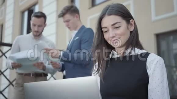 前景中漂亮的年轻女人用笔记本电脑工作的肖像两个成功自信的男人视频的预览图