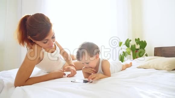 妈妈和儿子在卧室里看智能手机视频的预览图