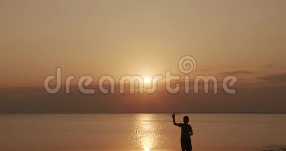 快乐的孩子带着玩具飞机在海上日落的背景下奔跑视频的预览图