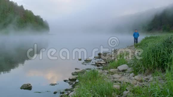 穿着蓝色夹克的人喜欢早晨在湖边散步视频的预览图