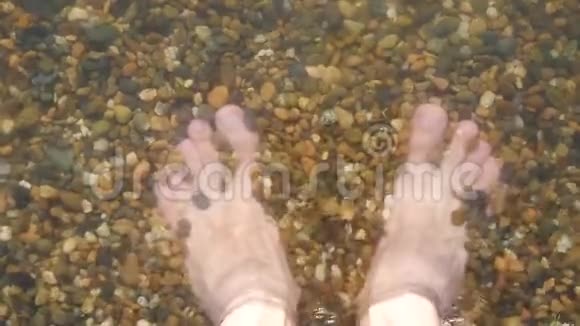 一个人光着脚在海边的鹅卵石滩上特写水洗了一个人的腿视频的预览图