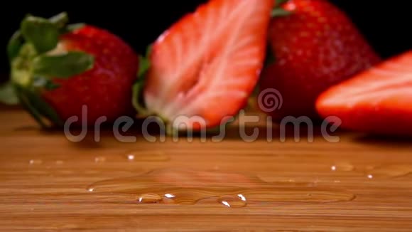 一个成熟的草莓落在潮湿的木板上视频的预览图