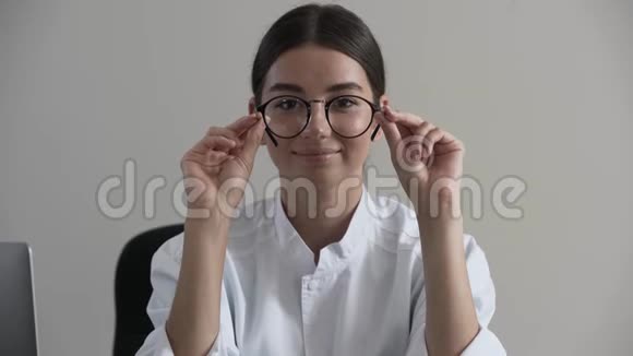 肖像可爱的年轻职业女医生手里拿着眼镜看着相机注意力从面部转移视频的预览图
