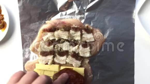 男人把猪油奶酪腊肠和晒干的西红柿放在鸡肉上使得卷视频的预览图