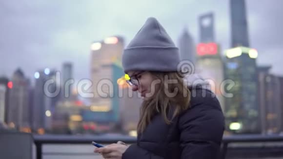 一个穿黑夹克戴黑帽子的年轻女孩慢慢地走着在电话里重写视频的预览图