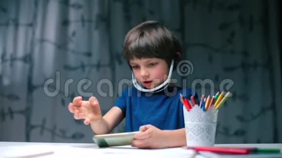 一个坐在桌子旁的男孩使用智能手机视频的预览图