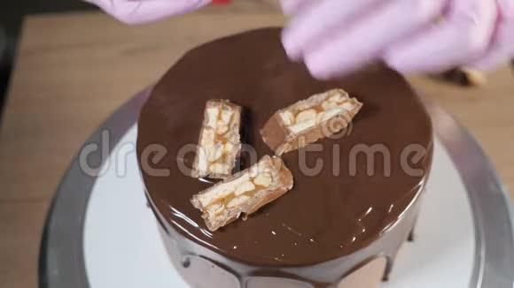 特写糕点厨师他的手正在用巧克力片和花生装饰蛋糕视频的预览图