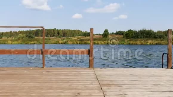 在蓝色多云的天空背景下湖上的木墩库存录像木质平台的自然庭园景观密集视频的预览图