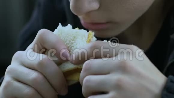 饥饿的无家可归的男孩吃三明治靠慈善生活的孩子贫穷的特写视频的预览图