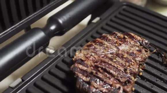 美味的牛排准备吃肉用草药腌制在家用电烤架上视频的预览图