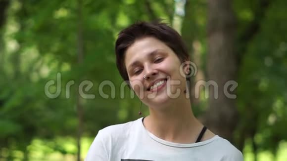 浪漫的年轻黑发女人在一片绿色的树林里嬉戏和微笑穿着邋遢视频的预览图