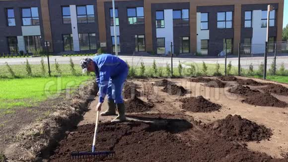 年轻人在花园里用耙子平整肥沃的土壤静态拍摄视频的预览图