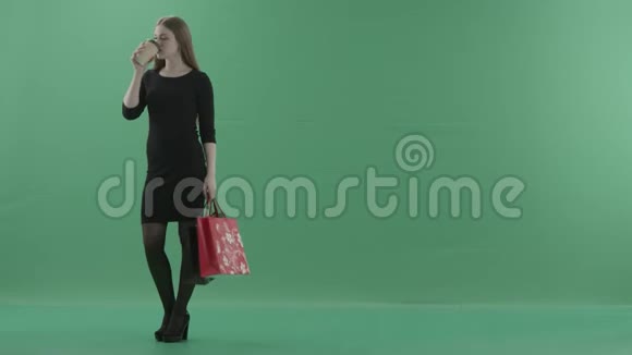 穿着黑色小裙子的漂亮女人正在喝咖啡或茶拿着她的购物袋她站在左边视频的预览图