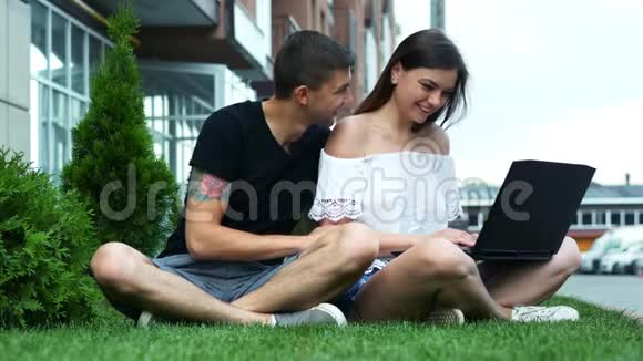 快乐的一对夫妇用笔记本电脑在线购买选择商品坐在草地上视频的预览图