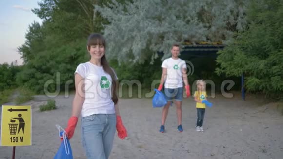 拯救星球年轻的志愿者妇女戴着橡胶手套的肖像垃圾袋靠近背景男性和背景男性的指针标志视频的预览图