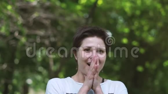 深受感动的黑发女人微笑着在一片木林中拍手视频的预览图