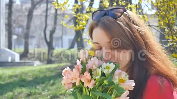 情绪激动的年轻女子戴着太阳镜站在外面捧着一大束五颜六色的鲜花在清晨微笑视频的预览图