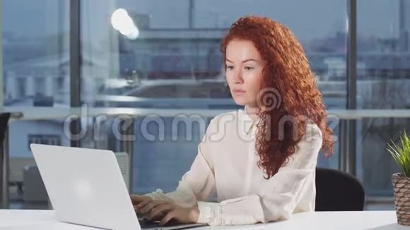 漂亮的女人用笔记本电脑看监视器屏幕视频的预览图