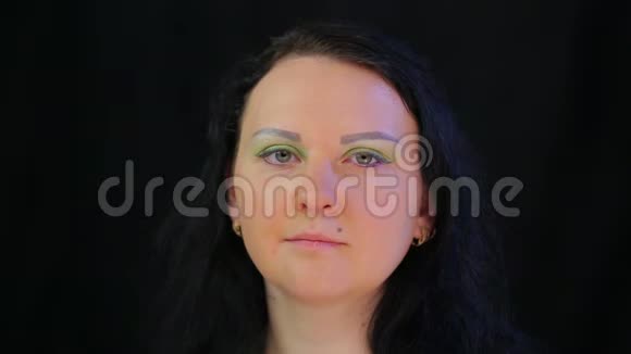 一个深色头发的女人着一张有着亮绿色阴影的眼妆的脸视频的预览图