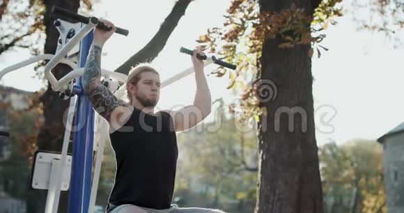 男性运动员在户外运动年轻的肌肉男训练他的手臂强壮适合男孩在公园锻炼健身视频的预览图
