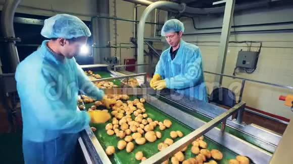 两个穿工作服的男人正在加工土豆块茎视频的预览图