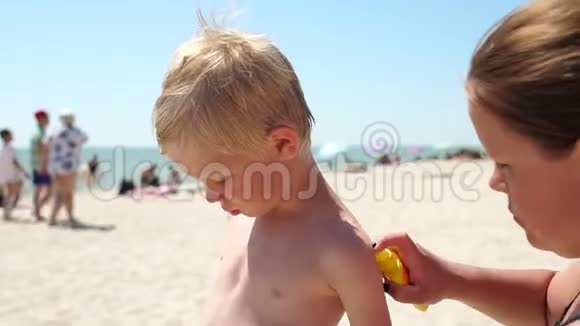 母亲在海滩上给孩子的皮肤涂防晒霜视频的预览图
