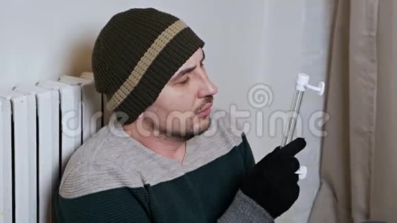 人检查加热电池的温度寒冷的冬天寒冷的房子公寓一个人在附近取暖视频的预览图
