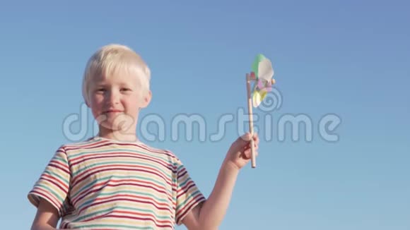 金发男孩在慢动作地玩风车公园视频的预览图