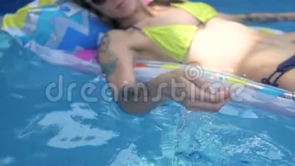 年轻迷人的女人在床垫上的游泳池里洗澡从上面看度假的女人在游泳池里游泳视频的预览图