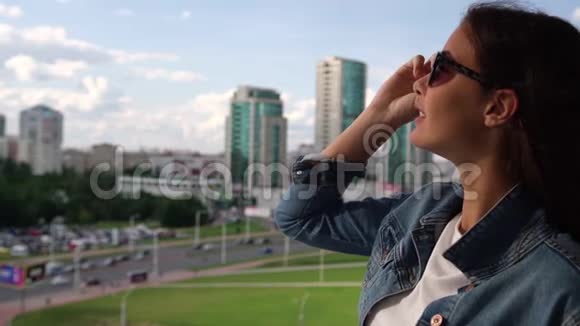 戴着黑墨镜的年轻黑发美女看城市风景视频的预览图