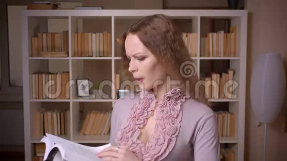 白种人波浪型金发金发的教师在图书馆读书时专心致志的画像视频的预览图