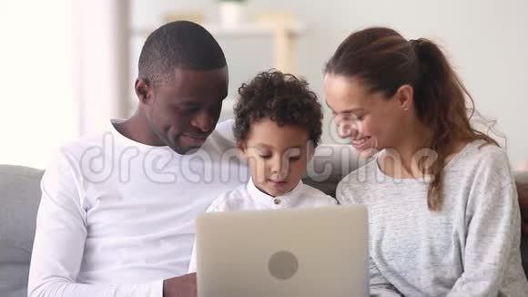 快乐的跨种族家庭爸爸妈妈和小儿子使用笔记本电脑视频的预览图