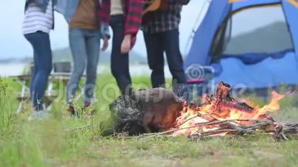 在草地草地和山湖背景下用跳舞的人和露营帐篷特写篝火旅行和度假视频的预览图