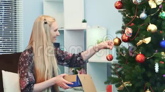 快乐的女人把玩具挂在圣诞树上从盒子里拿出来视频的预览图