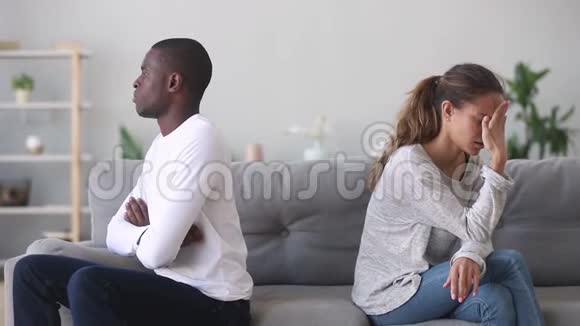 一对不快乐的顽固的混合种族的年轻夫妇分别坐在沙发上视频的预览图