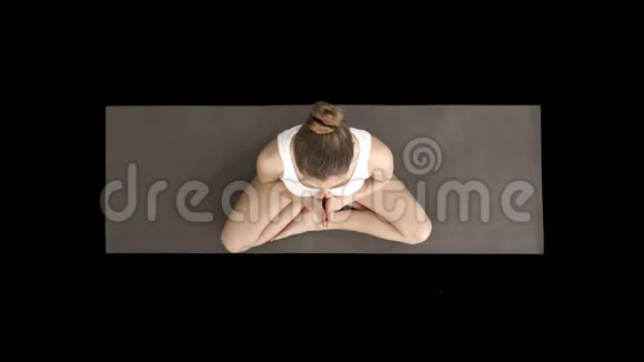 美丽的女人在莲花姿势中练习瑜伽伸展手在头上靠在一边另一边阿尔法视频的预览图
