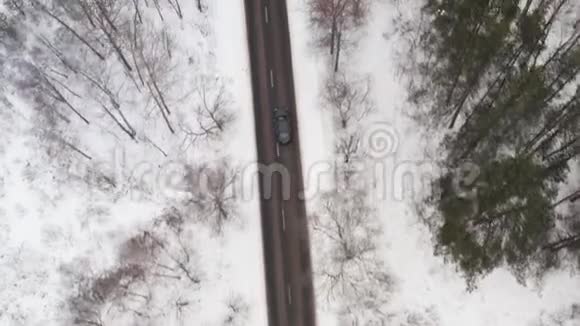 在冬季森林道路上驾驶汽车的鸟瞰图冬季风景顶级追踪镜头视频的预览图