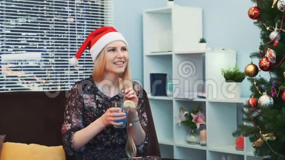 带上微笑的女人戴上圣诞帽举杯畅饮鸡尾酒视频的预览图