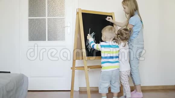 三个孩子正在用蜡笔在木板上画画视频的预览图