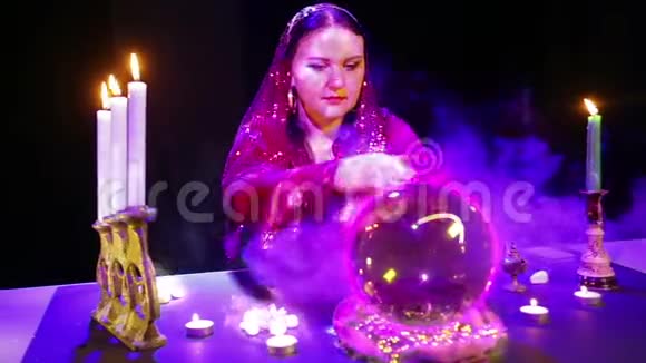 一个吉普赛女人在一个魔法沙龙里烟雾缭绕在水晶球上猜测里面出现了一个心脏征视频的预览图