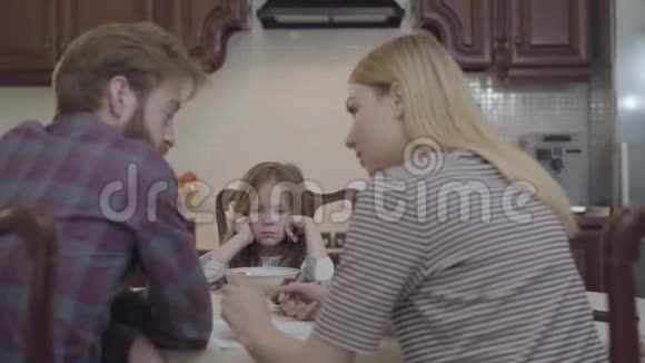 年轻男女坐在餐桌前吃早餐的后景父母讨论重要的事情小女孩视频的预览图