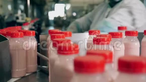 食品包装食品工厂输送机食品生产工厂工人从移动传送带上拿着酸奶的瓶子视频的预览图